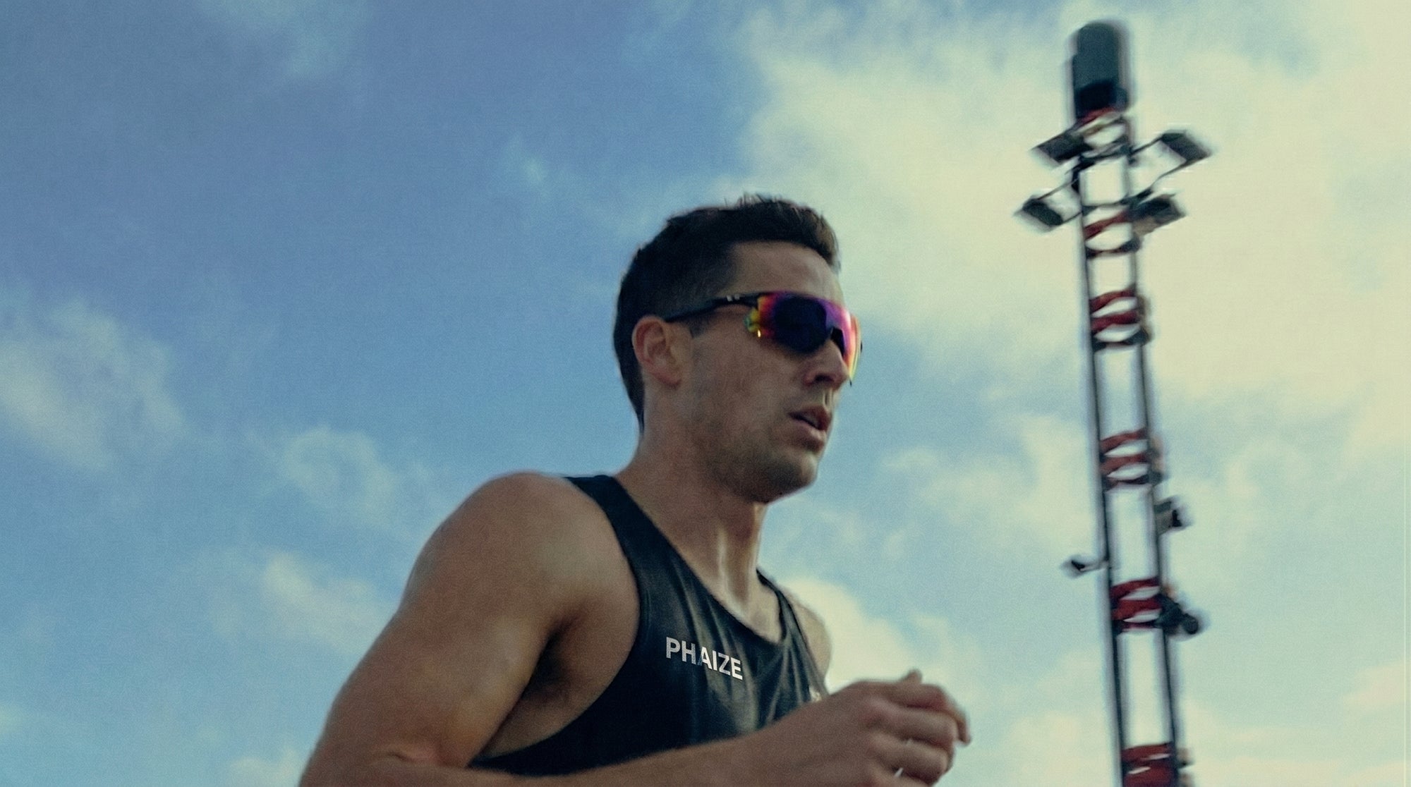 Ausdauerathlet mit Sportbrille beim Sprint. Muskelregeneration und Gelenkschutz für Leistungssportler durch PHAIZE Magnesium spray.